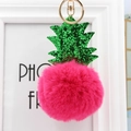 Gros plan sur le porte-clés ananas en fourrure fuchsia avec fermoir en métal doré - Rouge Rose
