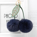 Detailed close-up of navy blue faux fur cherry keychain with green leaves and gold hardware - Navy Blue