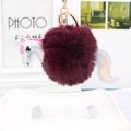 Close-up of fluffy unicorn keychain with burgundy pompom and laser silver details - Deep purple
