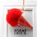 Close-up of red plush fur ice cream keychain with yellow grid stitching and gold lobster clasp - Red