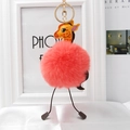 Close-up of a plush pink giraffe bag charm with a golden ring and faux fur ball - Orange
