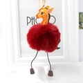 Close-up of fluffy red giraffe keychain with soft fur ball and gold metal ring - Burgundy