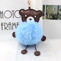 Detail of blue plush pompom bear keychain with brown leather accents and gold clasp - Blue
