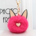 Détail d'un porte-clés pompon chat rose moelleux avec oreilles et fermoir mousqueton doré - Rose rouge