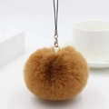 Detailed close-up of a soft brown faux fur pompom keychain with a black lanyard cord - Coffee