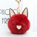 Detail van rode pluchen pompon sleutelhanger met kattenoren en roze hartjes hanger - Bordeauxrood