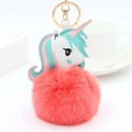 Detail eines Einhorn-Plüsch-Schlüsselanhängers mit rosa Kunstfell-Bommel und Goldring - Orangerot