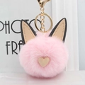 Gros plan d'un porte-clés pompon rose avec oreilles de chat en cuir et fermoir doré - Rose Clair
