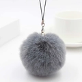 Detail of soft grey faux rabbit fur pom pom with silver lobster clasp and black lanyard - Medium Grey