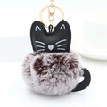 Detail of cute cat keychain featuring a black faux leather head and fluffy bicolor pom pom - Brown And White With Gold Ring
