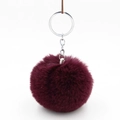 Detailed close-up of a burgundy faux rabbit fur pompom with silver metal key ring and chain - Deep purple