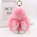 Detail van een roze pluche konijn met witte leren pootjes en een gouden sleutelhanger - Lichtroze