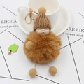 Detail of cute brown sleeping baby plush keychain with gold clasp on white cup - Coffee