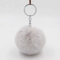 Detailed view of an 8cm light grey faux fur pompom keychain with a silver metal ring - Grayish White