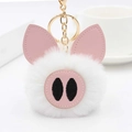 Détail d'oreilles et museau de cochon en simili cuir rose sur un porte-clés pompon blanc - Blanc