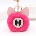 Gros plan d'un porte-clés pompon cochon rose en peluche avec un fermoir doré brillant - Rose rouge