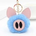 Détail d'un porte-clés cochon en peluche bleue avec oreilles en cuir et fermoir doré - Bleu