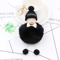 Détail d'un porte-clés poupée bébé endormi en peluche avec pompon noir et un joli nœud - Noir
