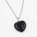 Detailed close-up of a heart-shaped black stone pendant with a silver-colored chain - Black