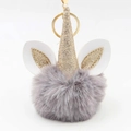Close-up of a plush unicorn keychain with grey faux fur ball and golden sequin horn - Light Gray
