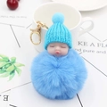 Close-up of a blue sleeping baby plush keychain with knitting hat and fur ball accessory - Blue