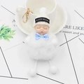 Détail d'un porte-clés poupée bébé endormi en peluche avec bonnet blanc et nœud papillon - Blanc