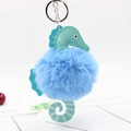 Close-up of blue fluffy pompom seahorse keychain with mint green leather details - Blue