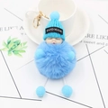 Detailed close-up of a blue sleeping baby doll plush keychain with fluffy fur ball and gold clip - Blue