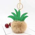 Detail of pineapple plush keychain with faux fur, green leather leaves, and gold chain - Khaki