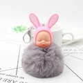 Detailed macro view of a fluffy gray faux fur keychain with a cute pink rabbit sleeping baby - Light Gray