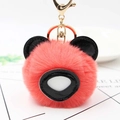 Gros plan du porte-clés ours en peluche corail avec oreilles noires et anneau doré - Rouge Orangé