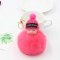 Gros plan du porte-clés poupée bébé pompon rose avec anneau doré sur table - Rouge pastèque
