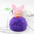Detail of creative sleeping baby doll with rabbit ears and a purple fluffy fur ball charm - Purple