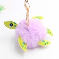 Dettaglio portachiavi a tartaruga in peluche lavanda con zampe in ecopelle verde e gancio - Diametro Pon Pon 8cm / Viola Chiaro