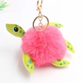 Dettaglio di un portachiavi a tartaruga in peluche rosa con ecopelle giallo-verde e oro - Diametro Pon Pon 8cm / Rosso Anguria