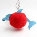 Close-up of a cute plush dolphin keychain with a red pom-pom and blue leather details - Red
