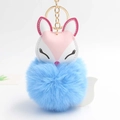 Close-up of sleeping fox charm with soft blue pom-pom and gold metal keychain - Blue