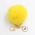 Detail eines flauschigen gelben Pelz-Schlüsselanhängers mit Perlen-Schleifen-Anhänger - Pompon Durchmesser 8cm / Gelb