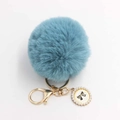 Close-up of blue faux fur pompom keychain with golden clasp and pearl bow charm - Pom Pom Diameter 8cm / Lake Blue
