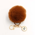 Detail of caramel faux fur pompom keychain with golden metal ring and pearl bow charm - Pom Pom Diameter 8cm / Brown