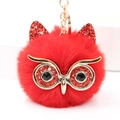 Détail macro d'un porte-clés hibou en peluche rouge avec des accents dorés et des yeux scintillants - Rouge