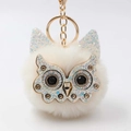 Close-up of white plush owl keychain with sparkling gold metal face and crystal eyes - Off White
