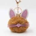Macro view of a brown plush bunny keychain with pink glitter ears and gold hardware - Coffee