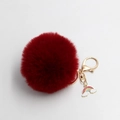Detail view of the burgundy fluffy pompom keychain with golden clasp and rainbow charm - Burgundy