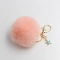 Detail of pink starfish plush pompom keychain with golden metal clasp and blue charm - Pink