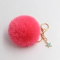 Detail of fluffy rose red faux fur pompom with golden metal clasp and blue glitter starfish - Watermelon red