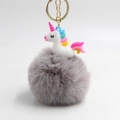Detail of white resin unicorn pendant with soft grey faux fur pompom and gold keychain - Light Gray