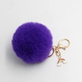 Detail view of purple faux fur pompom keychain with a golden clasp and rainbow charm - Purple