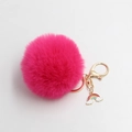 Detail of plush fuchsia faux fur keychain with golden clasp and cute rainbow charm - Rose Red