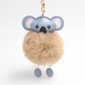 Detail of a fluffy koala pompom keychain with faux fur, blue ears and golden metal clasp - Khaki